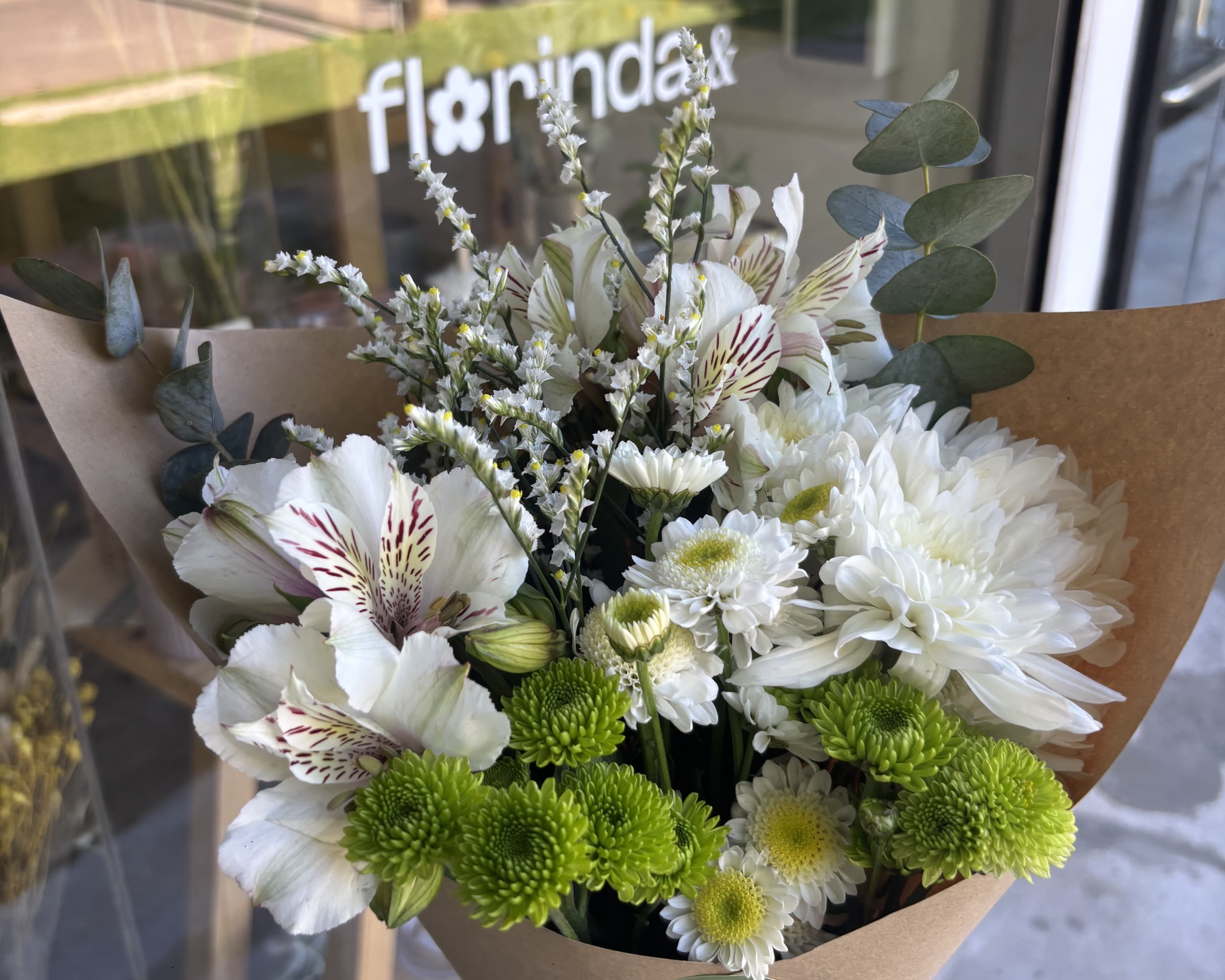 ramo flores blancas con fondo vidriera del local