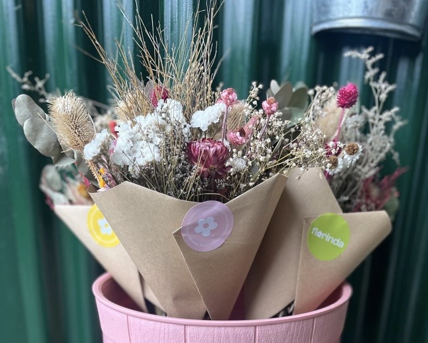 ramos secos en un balde rosa con fondo de chapa verde