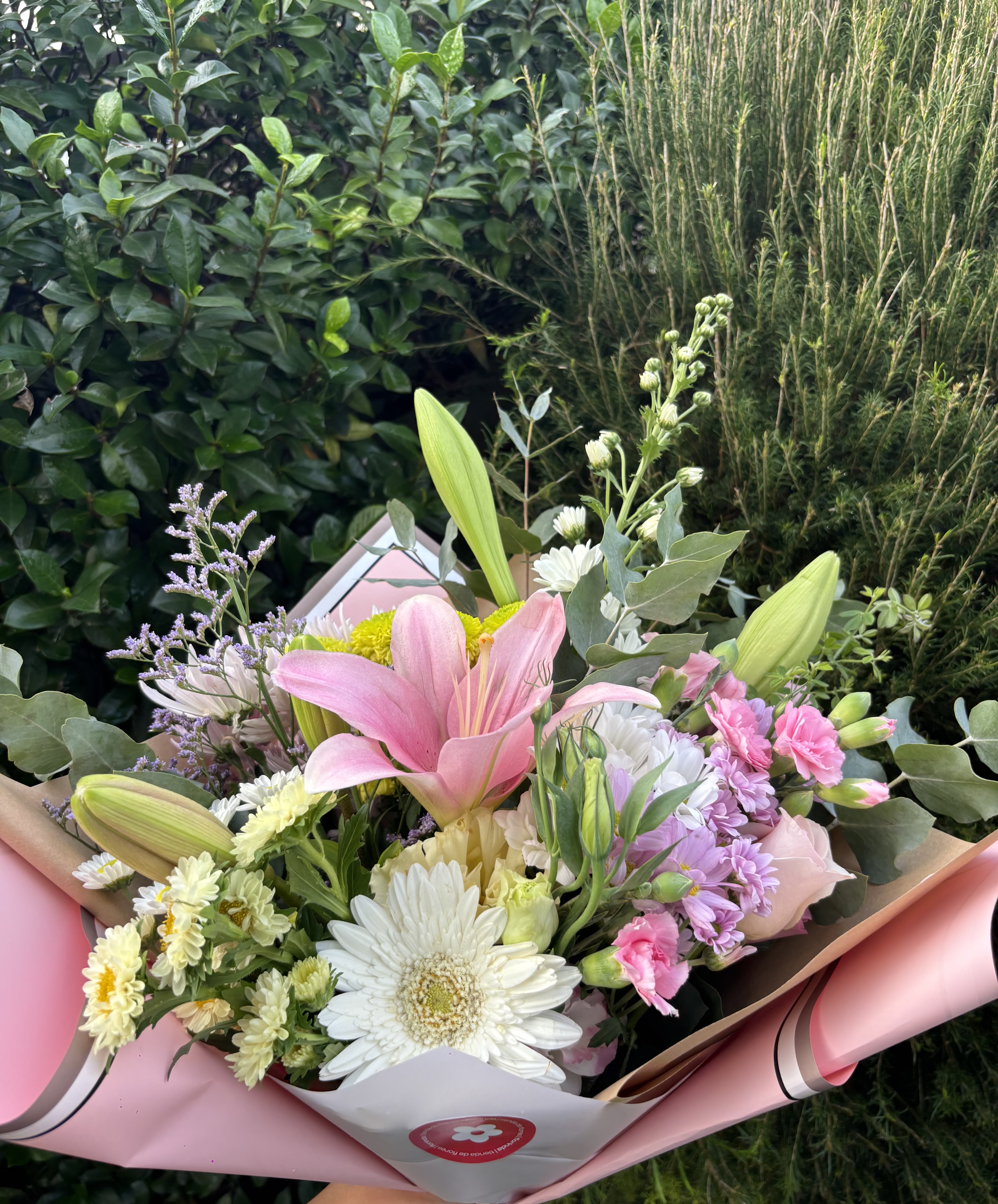 ramo flores de estación con papel rosa y fondo de hojas verdes